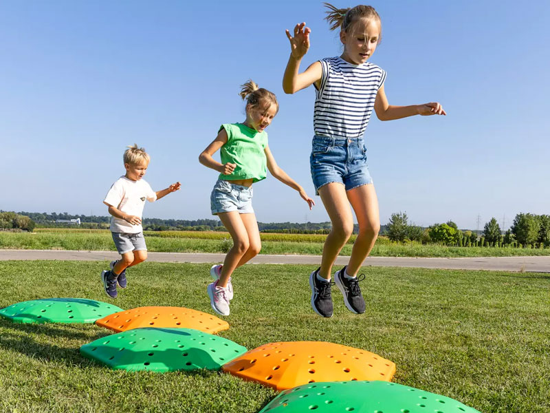 Kinderen springen op de BounceCloud trampoline van Eurotramp in een groene buitenomgeving